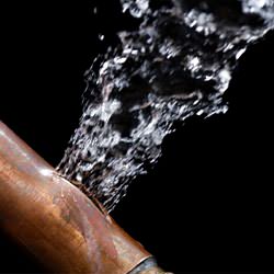 A bursting copper pipe in Ontario, with water gushing out.